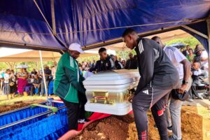 Casket of Evelyn Kujinga at Glen Forest Cemetery during funeral service, carried to the grave, about to be lowered down. 