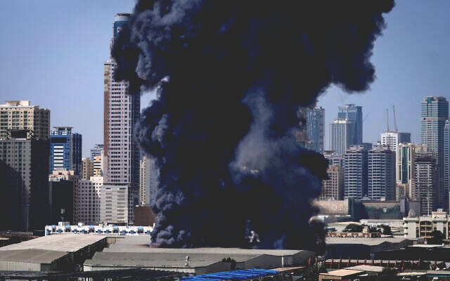 A black plume of smoke rises from a warehouse at the industrial area of Sharjah City in the United Arab Emirates following reports of Iranian strikes in Dubai, United Arab Emirates, March 1, 2026. (AP Photo/Altaf Qadri)
