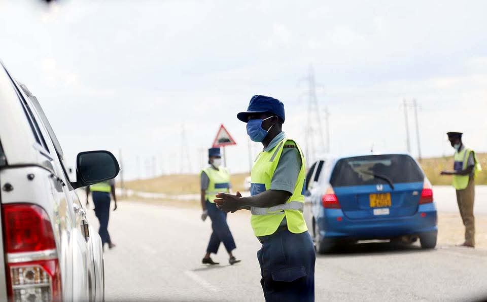 A Zimbabwe Republic Police officer engages a motorist at a roadblock mounted at Mubvuku turn off along Harare-Mutatre highway today to enforce government measures to combat the spread of Covid-19